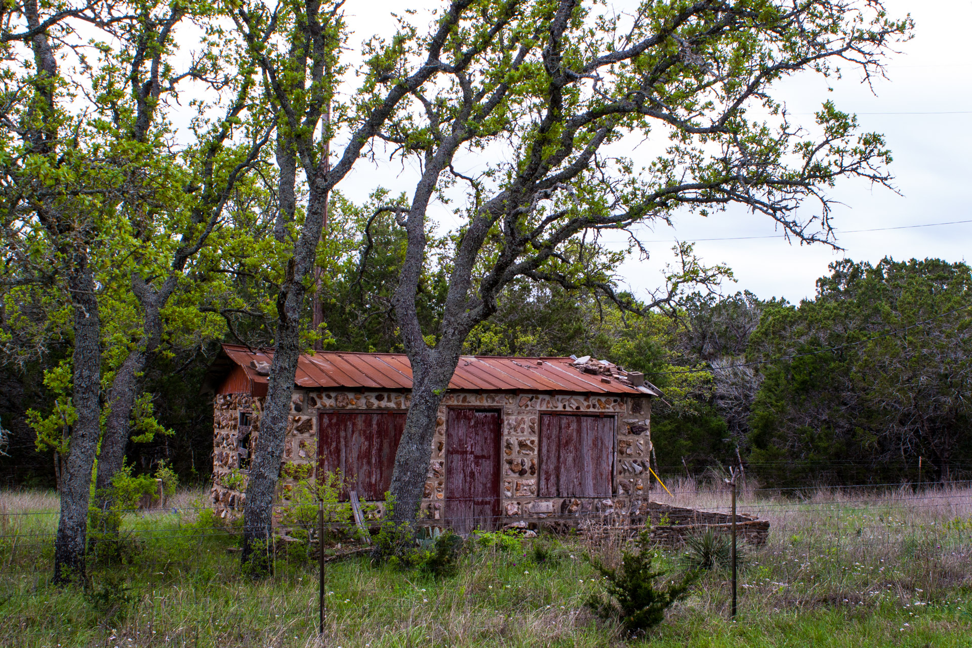 Burnet, Texas - A Red Stone Cottage With Bluebonnets (angle left)